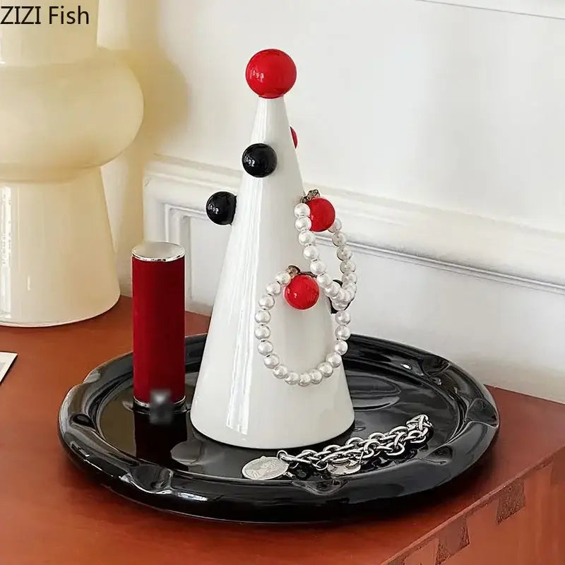 White ceramic jewelry stand with red and black accents displaying pearl bracelets and silver chain decorbites christmas tree