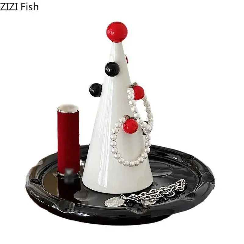 White ceramic DecorBites Christmas tree jewelry stand with red and black ornaments holding pearl necklaces and silver chains