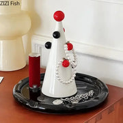 White ceramic DecorBites Christmas tree jewelry stand with red and black accents displaying pearl bracelets and silver chain
