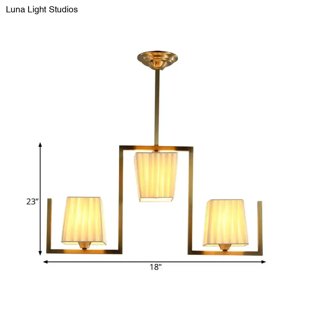 Gold-toned rectangular chandelier light kit with three warm pleated fabric shades for dining room ceiling light