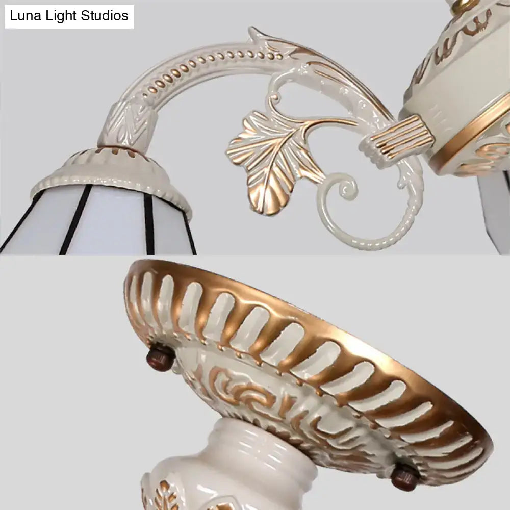 White and gold ornate ceramic wall sconce with leaf scrollwork detailing for a multi light chandelier ceiling light with white glass