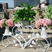 White wrought iron classic tall plant stand with leaf and vine scrollwork for indoor and outdoor use