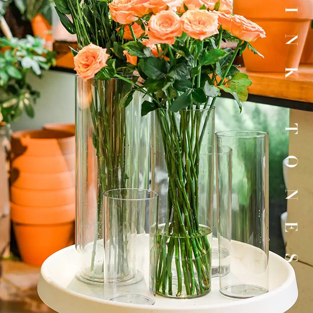 DecorBites clear acrylic cylinder vases in varying heights holding peach roses with green leaves for weddings