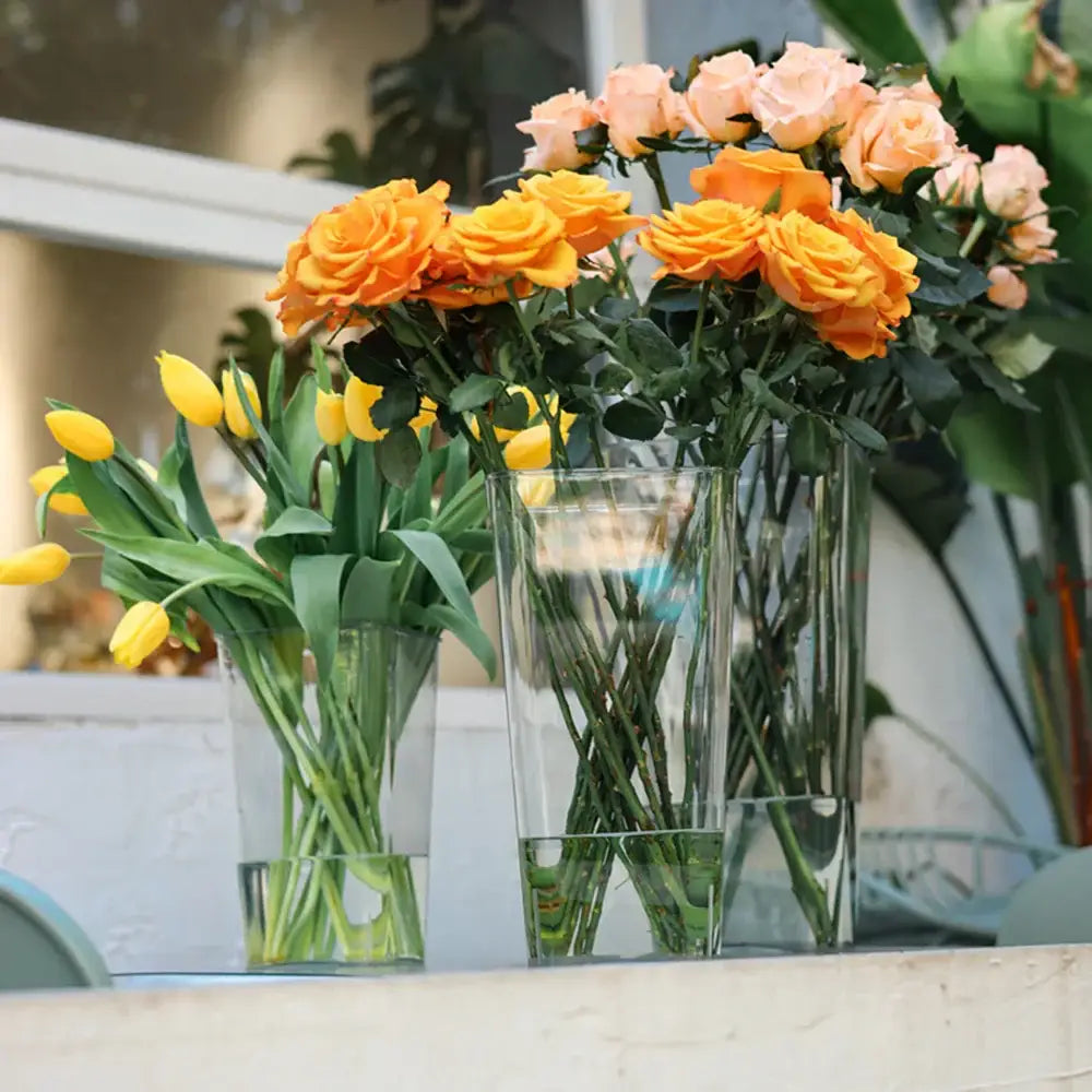DecorBites clear acrylic hurricane flower vase large size holds vibrant orange roses and yellow tulips in tall glass design