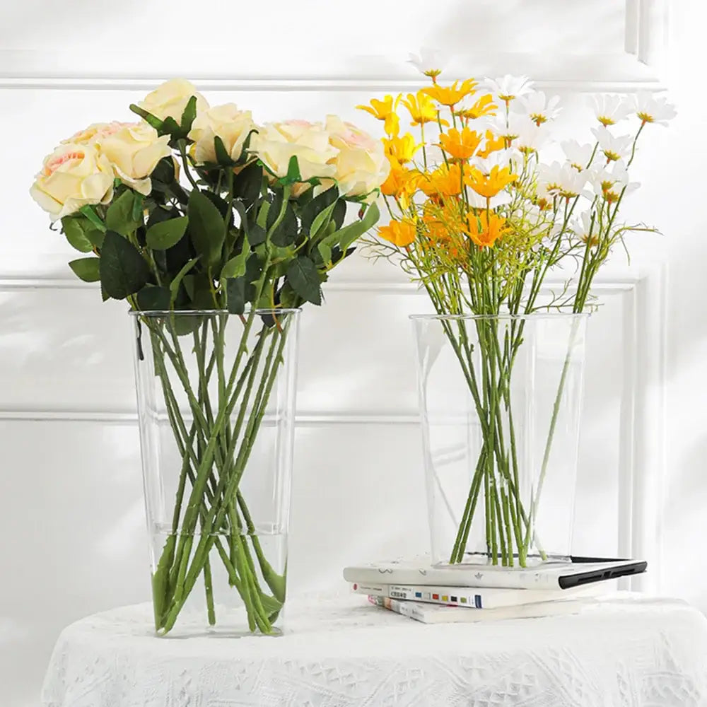 Two clear acrylic hurricane flower vases by DecorBites holding cream roses and yellow and white daisies