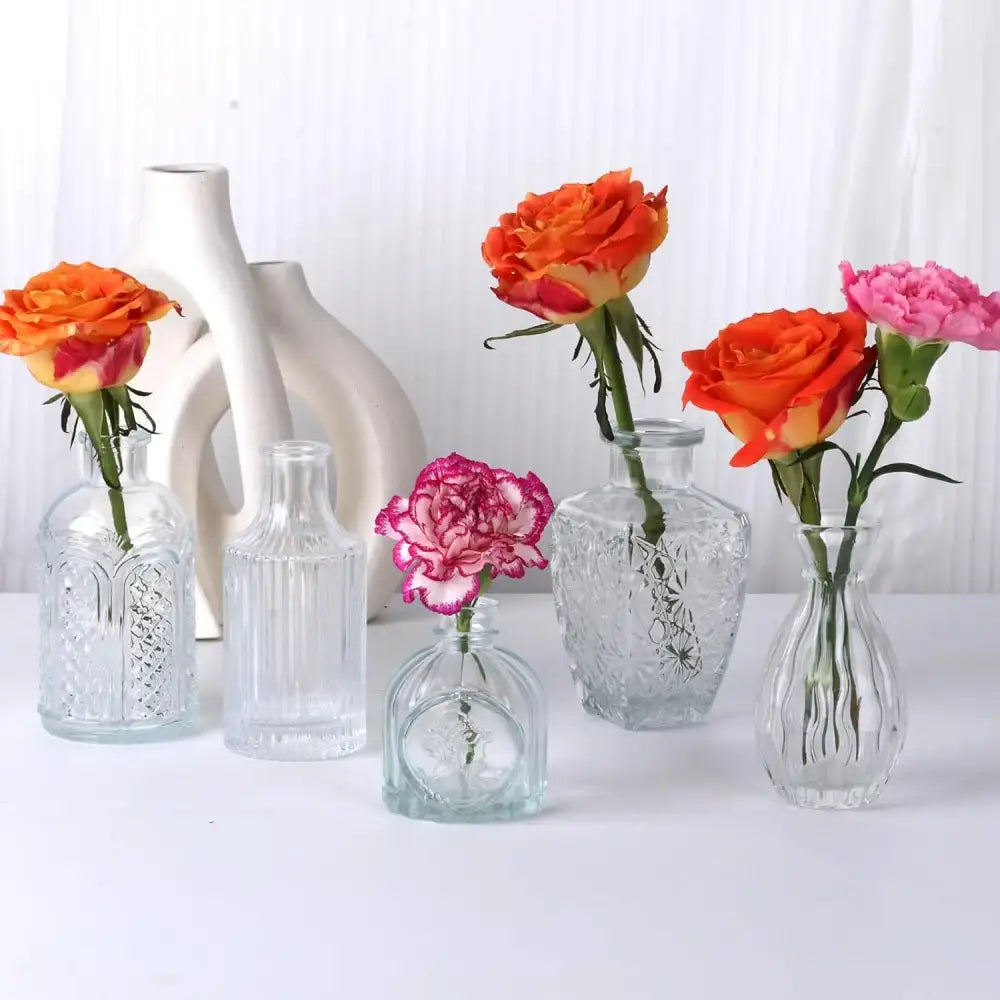 Decorbites™ clear glass bud vases with intricate etched patterns holding vibrant orange and pink roses