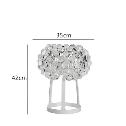 A sleek modern table lamp with a clear crystal bead spherical top and white metal base complementing decorbites clear gold pendant lights
