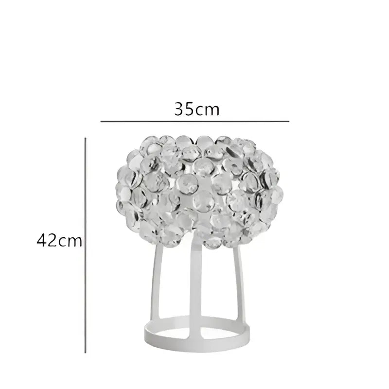 A sleek modern table lamp with a clear crystal bead spherical top and white metal base complementing decorbites clear gold pendant lights