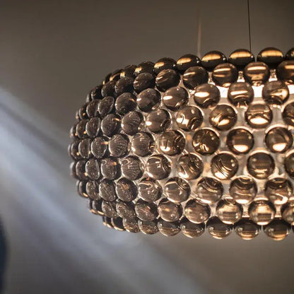 A modern spherical pendant light with polished dark amber glass orbs in decorbites clear gold acrylic finish