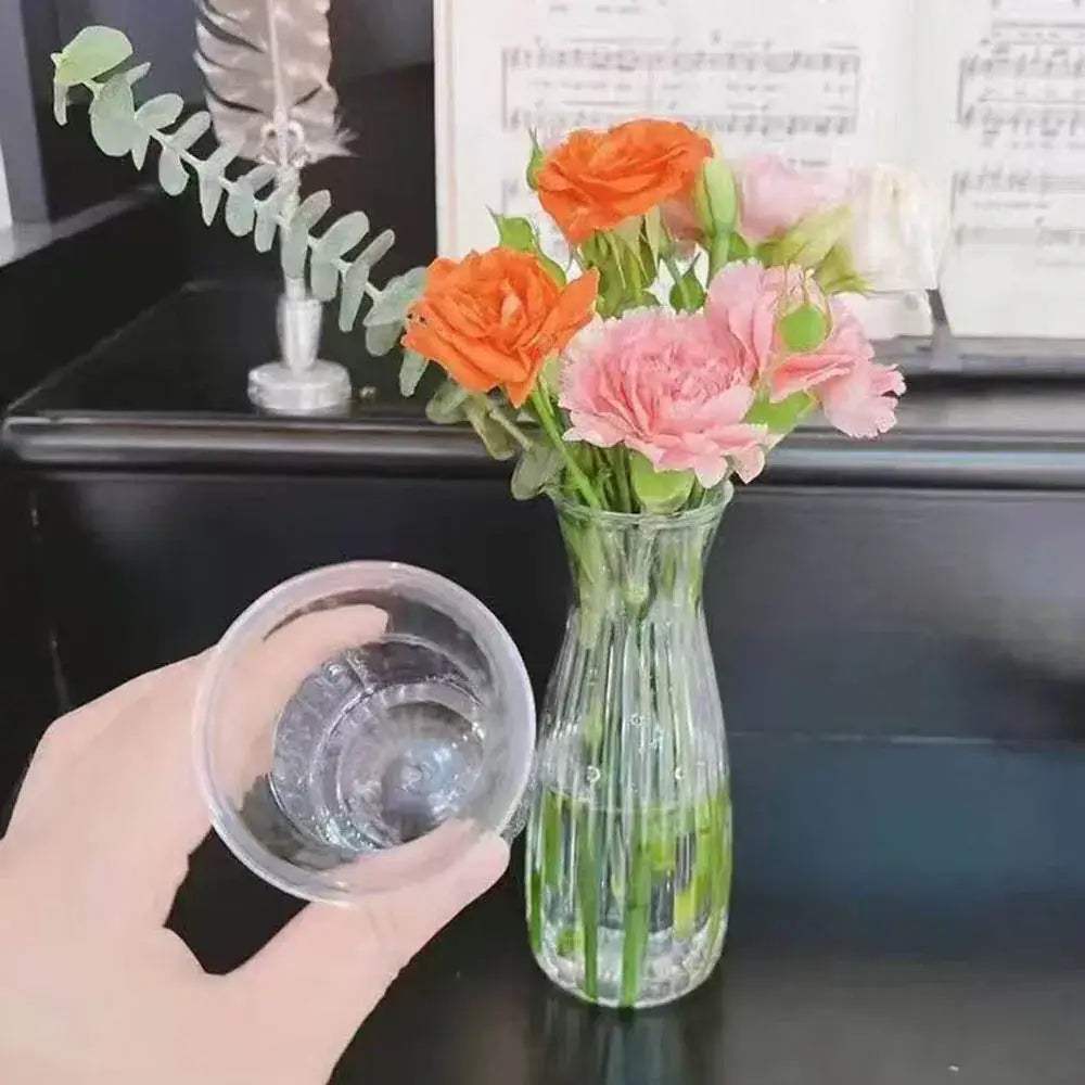 Clear Nordic plastic vase with vertical ridges holding orange and pink hydroponic flowers by DecorBites