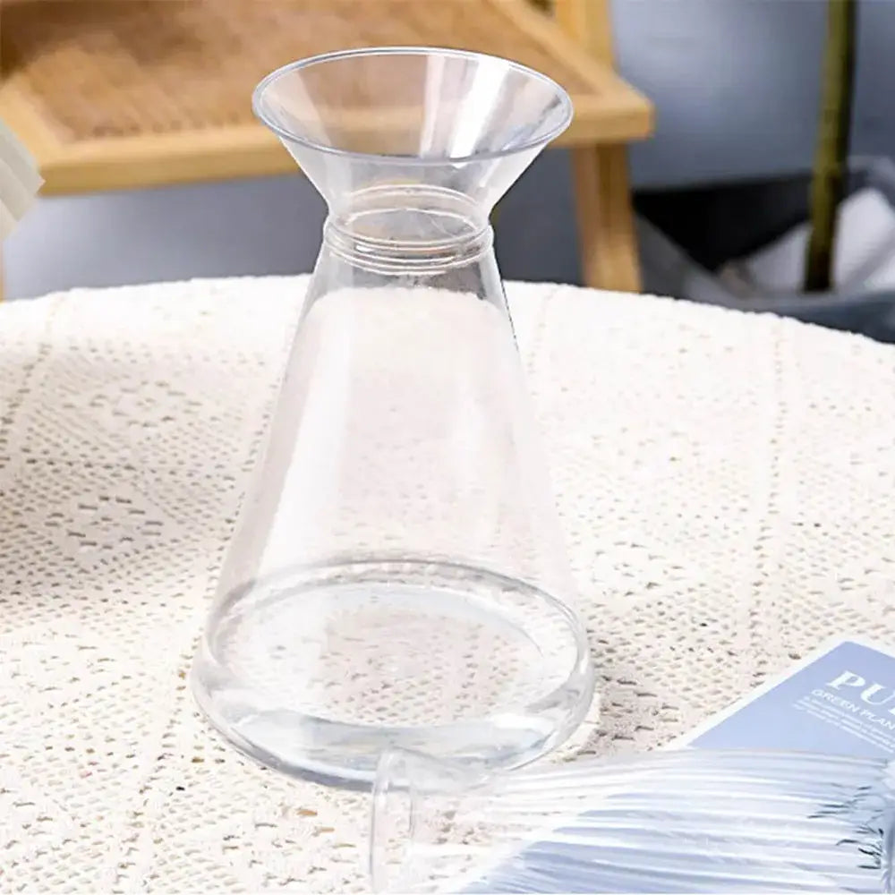 Clear glass DecorBites™ plastic vase with flared top and narrow neck for hydroponic flowers on textured white surface