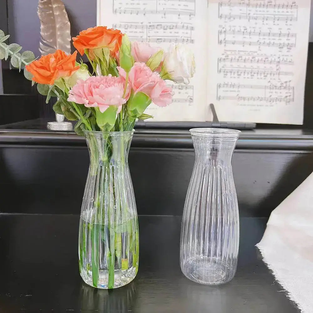 DecorBites clear nordic plastic vase with vertical ribbed texture holding orange and pink hydroponic flowers