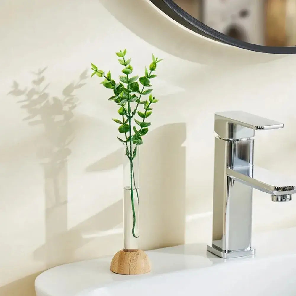 DecorBites™ clear plastic test tube vase with wooden base holding vibrant green eucalyptus sprigs for home decor