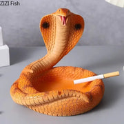 Orange resin decorbites cobra ashtray shaped like a detailed cobra with raised hood holding a cigarette in its open mouth
