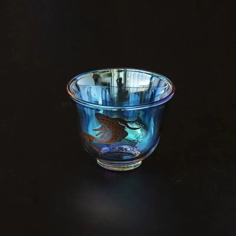 A translucent blue glass teacup with a golden fish design from decorbites colorful enamel glass collection