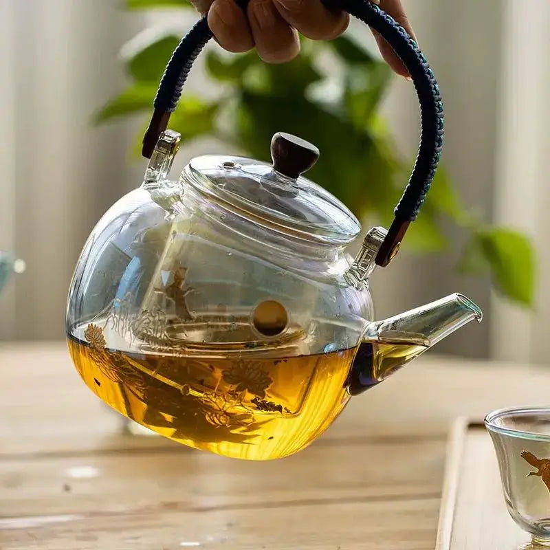 Clear glass teapot with dark blue braided handle wooden knob and etched floral designs by decorbites colorful enamel glass