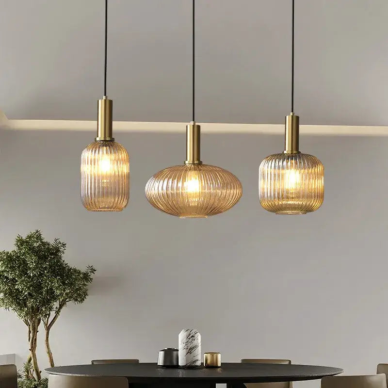Three elegant brass-finished pendant lights with ribbed amber colorful glass pendant lights for retro style dining space