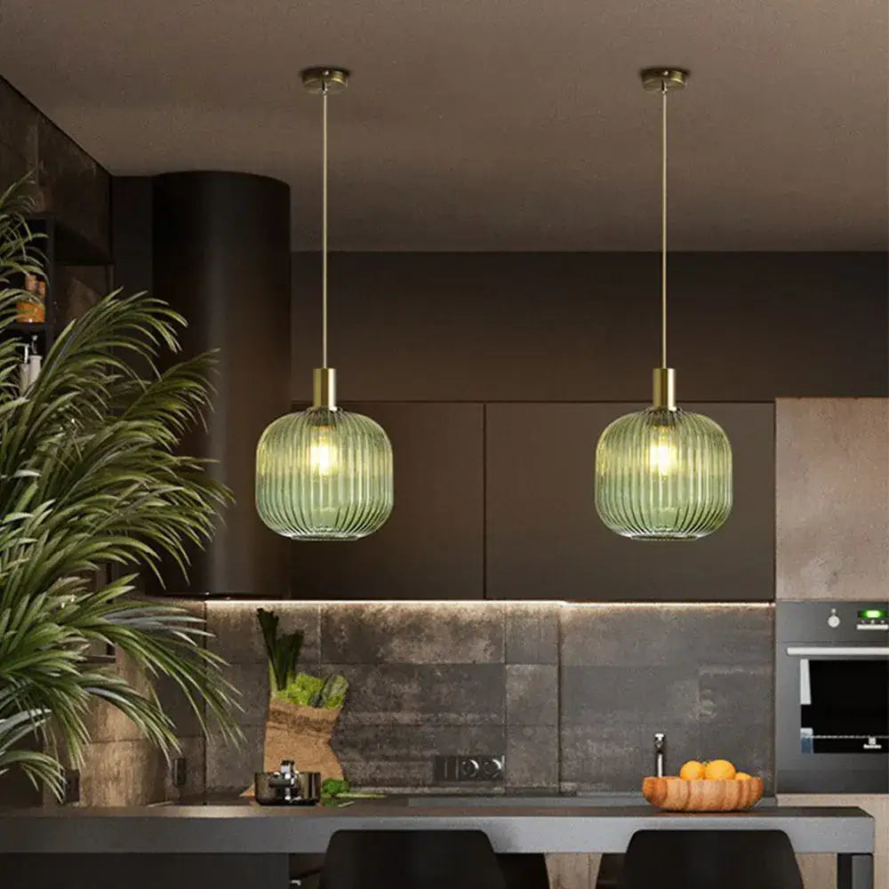 Two identical green ribbed glass pendant lights with brass fixtures hang from the ceiling for retro style decor