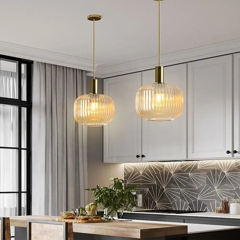 Two elegant gold-toned colorful glass pendant lights with ribbed amber glass shades for retro style decor