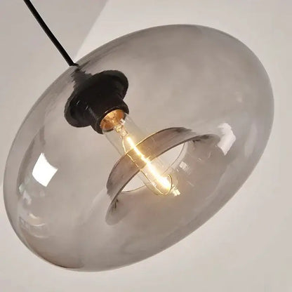 A sleek smoked glass colorful led pendant light with black cord and exposed filament bulb for restaurant decor