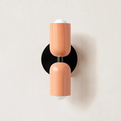 Coralbcolored modern wall sconce with glass shade white spherical accents and black circular base by decorbites