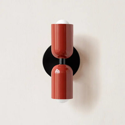 Red cylindrical modern wall sconce with glossy glass shade and black circular base from DecorBites™