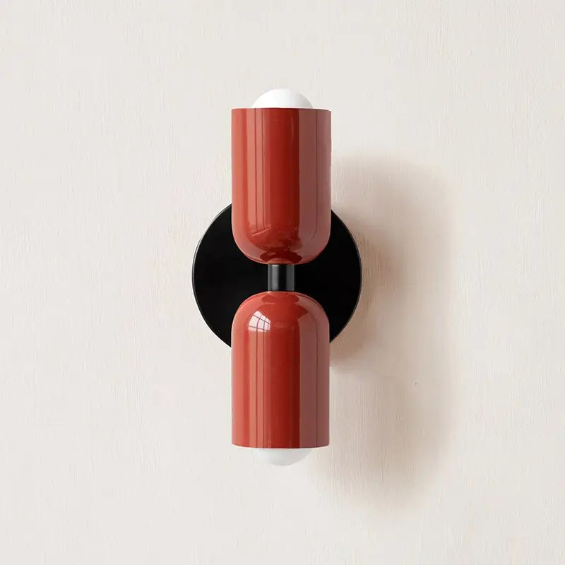 Red cylindrical modern wall sconce with glossy glass shade and black circular base from DecorBites™