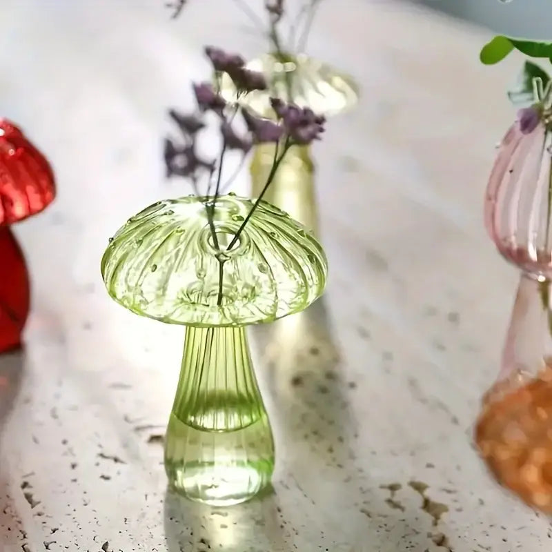 Transparente grünes Glas farbenfroher Pilzvase mit geripptem Stiel und gepunktetem Hut, der zarte violette Blumen hält