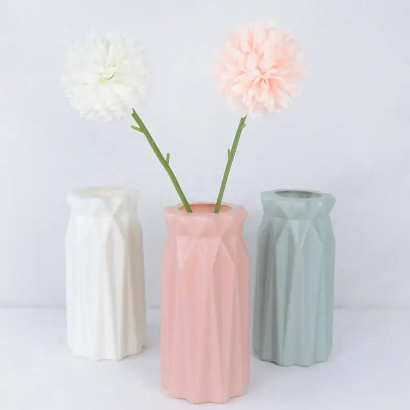DecorBites™ pastel pink geometric ceramic flower vase with faceted design holding two colorful plastic flowers