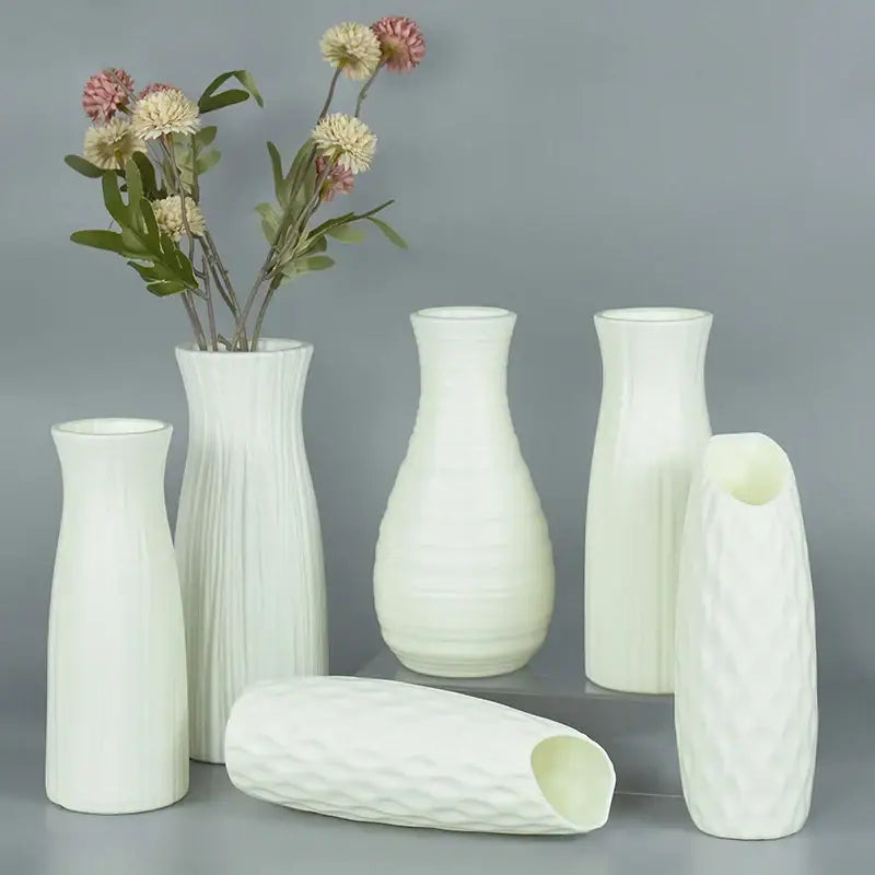 Set of six white ceramic flower vases with varied textures one holding pink and cream flowers for home décor