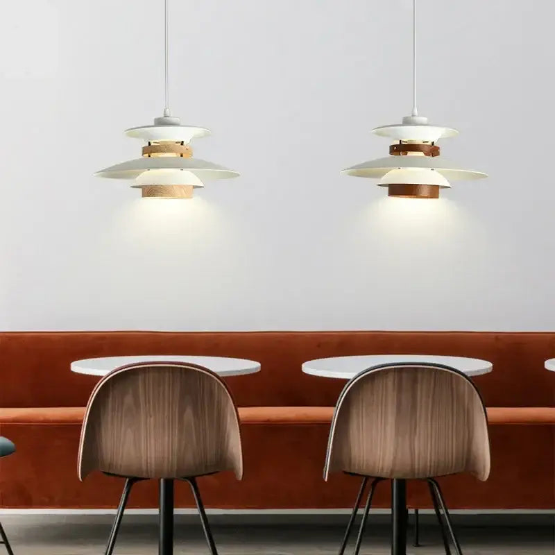 Two white and wood-toned decorbites colorful umbrella led chandeliers with modern tiered design hang above tables