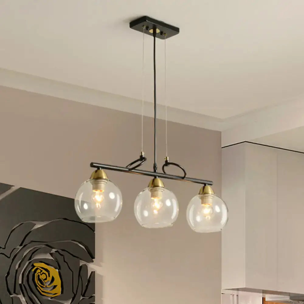 Modern black metal bar pendant light with three clear prismatic glass globe shades and brass accents for dining hall