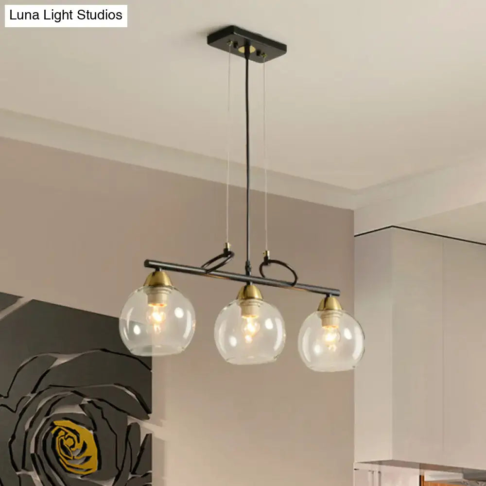 Modern black metal chandelier with three clear prismatic glass globe shades and brass accents for dining hall use