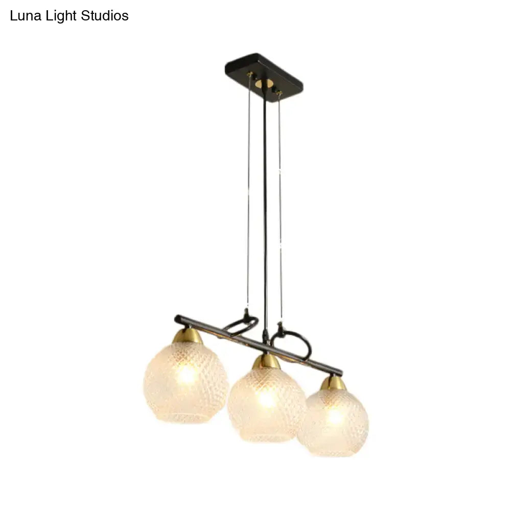 Modern black metal pendant light with three frosted prismatic glass globes and brass accents for dining hall use