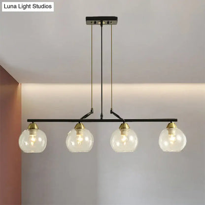 Black metal bar pendant light with four clear prismatic glass globe shades and brass accents for dining hall lighting