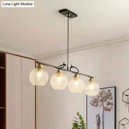 Modern black metal pendant light with four frosted globe shades and brass accents featuring clear prismatic glass for dining hall