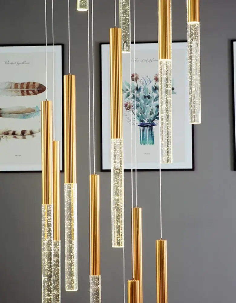 Gold-toned cylindrical pendant lights with clear sparkling crystals in a contemporary crystal chandelier for large staircase