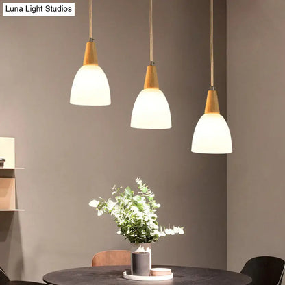 Three modern decorbites frosted glass dome pendant lights with beige glass domes and warm wood tops hanging by brass cords