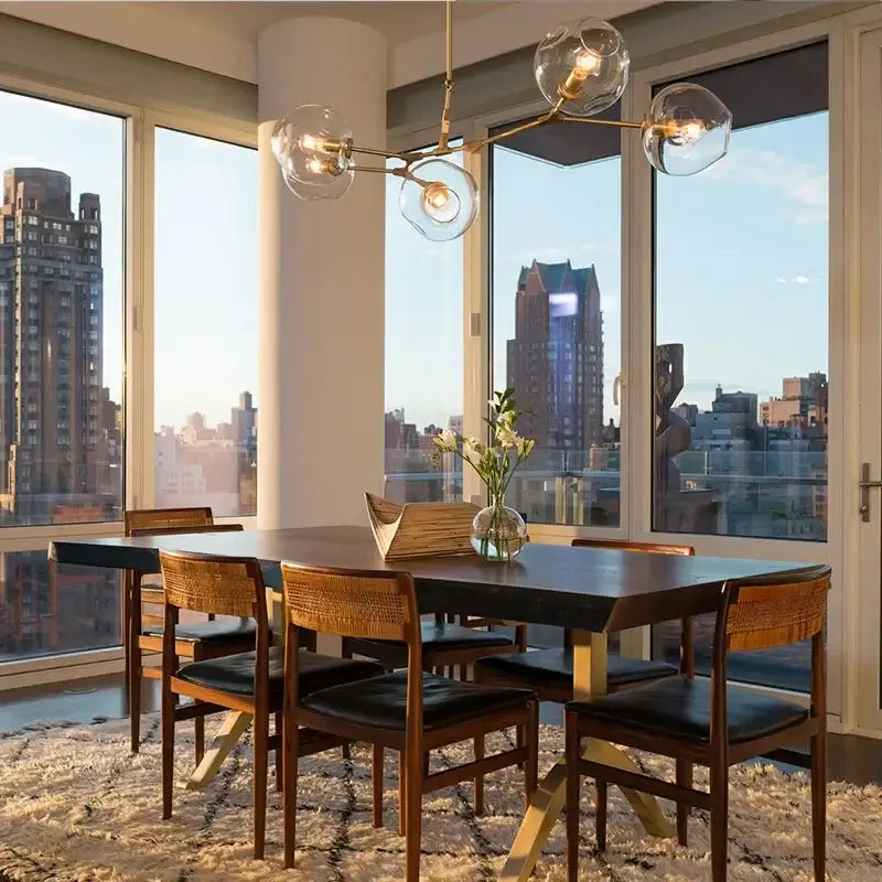Modern dining table with black top and wooden legs under a decorbites™ contemporary glass bubble chandelier