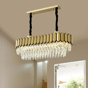Gold-toned rectangular oval island light with faceted crystal droplets on a sleek metal frame and led bulbs