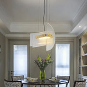 Modern white pendant light with gold geometric chandelier accents hanging above a dining table by DecorBites™