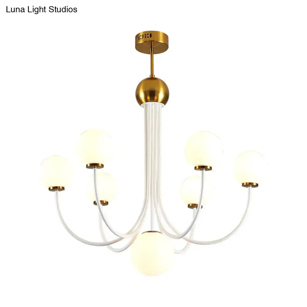 Modern chandelier with gold-finished metal frame and six frosted glass spherical shades for ceiling lighting