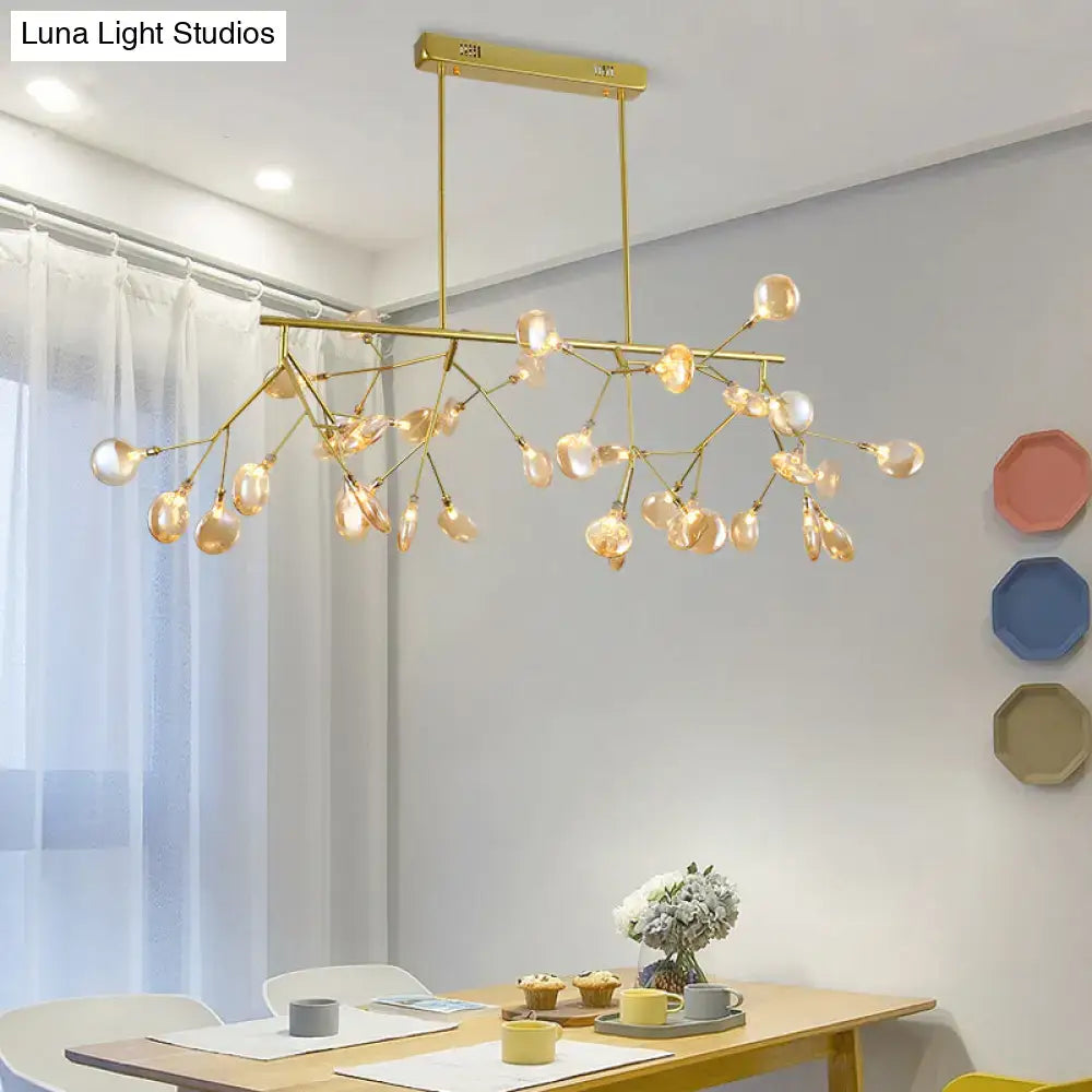 Gold-toned heracleum island pendant light with branching arms and amber glass globe bulbs for modern dining rooms