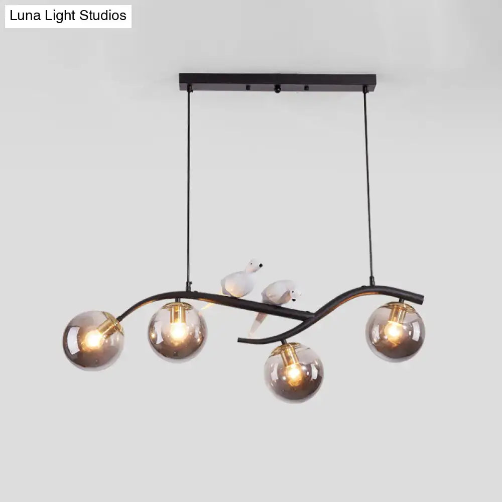Black metal chandelier with five smoke grey glass globes and white bird decor on curved arms from DecorBites™