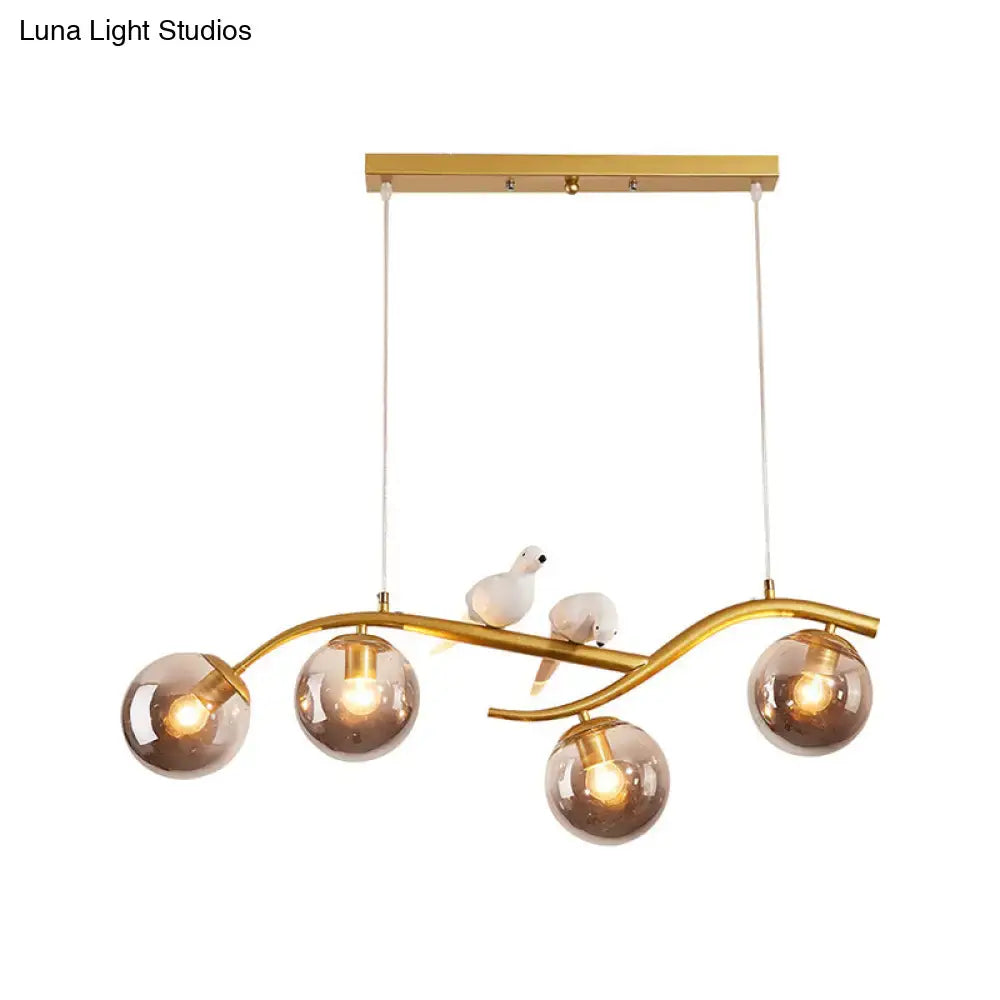 Gold-toned decorbites™ pendant light with five smoke grey cognac glass globes and white ceramic birds on curved metal arms