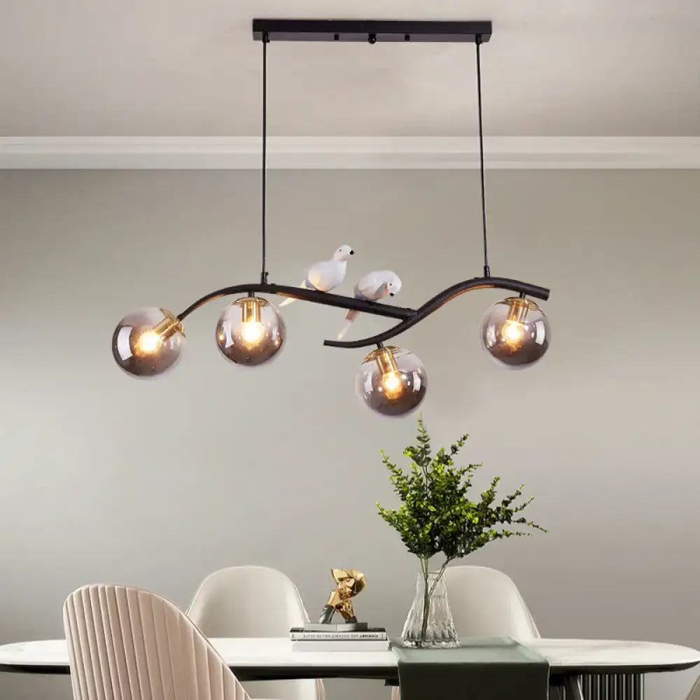 Modern black metal chandelier with five smoke grey globes and white ceramic bird decor on curved arms for island pendant lighting