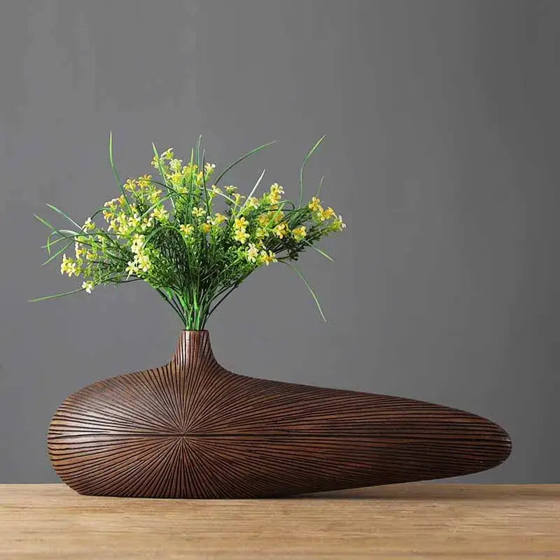 Decorbites™ contemporary resin vase in brown with radial grooves and narrow neck holding yellow flowers