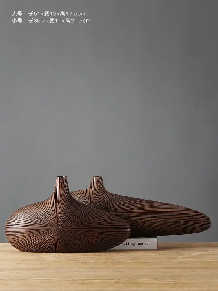 Two dark brown hand carved wooden vases with radiating grooves and elongated necks for contemporary resin vase decor