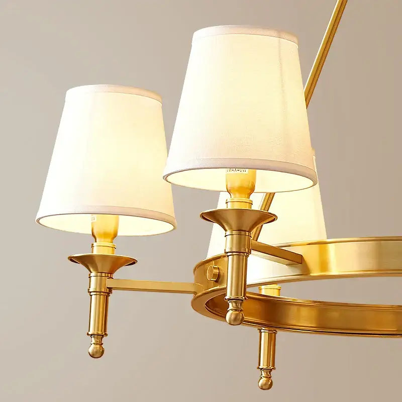 Gold-toned decorbites copper american chandelier with three cream fabric shades and ornate vintage metalwork for dining room