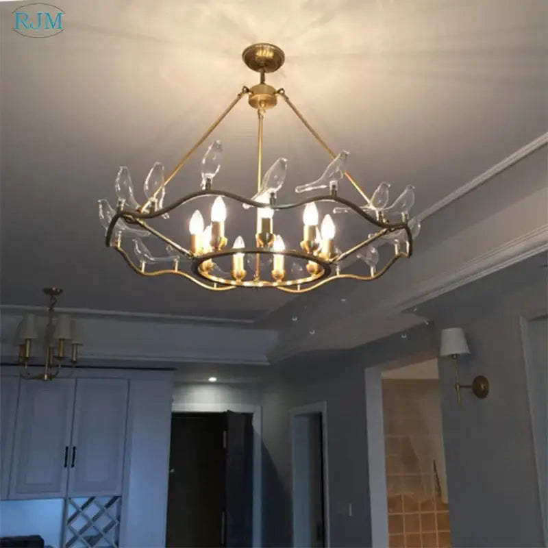 Gold-toned decorbites copper bird chandelier with clear glass bird ornaments and candle-style bulbs for dining room lighting